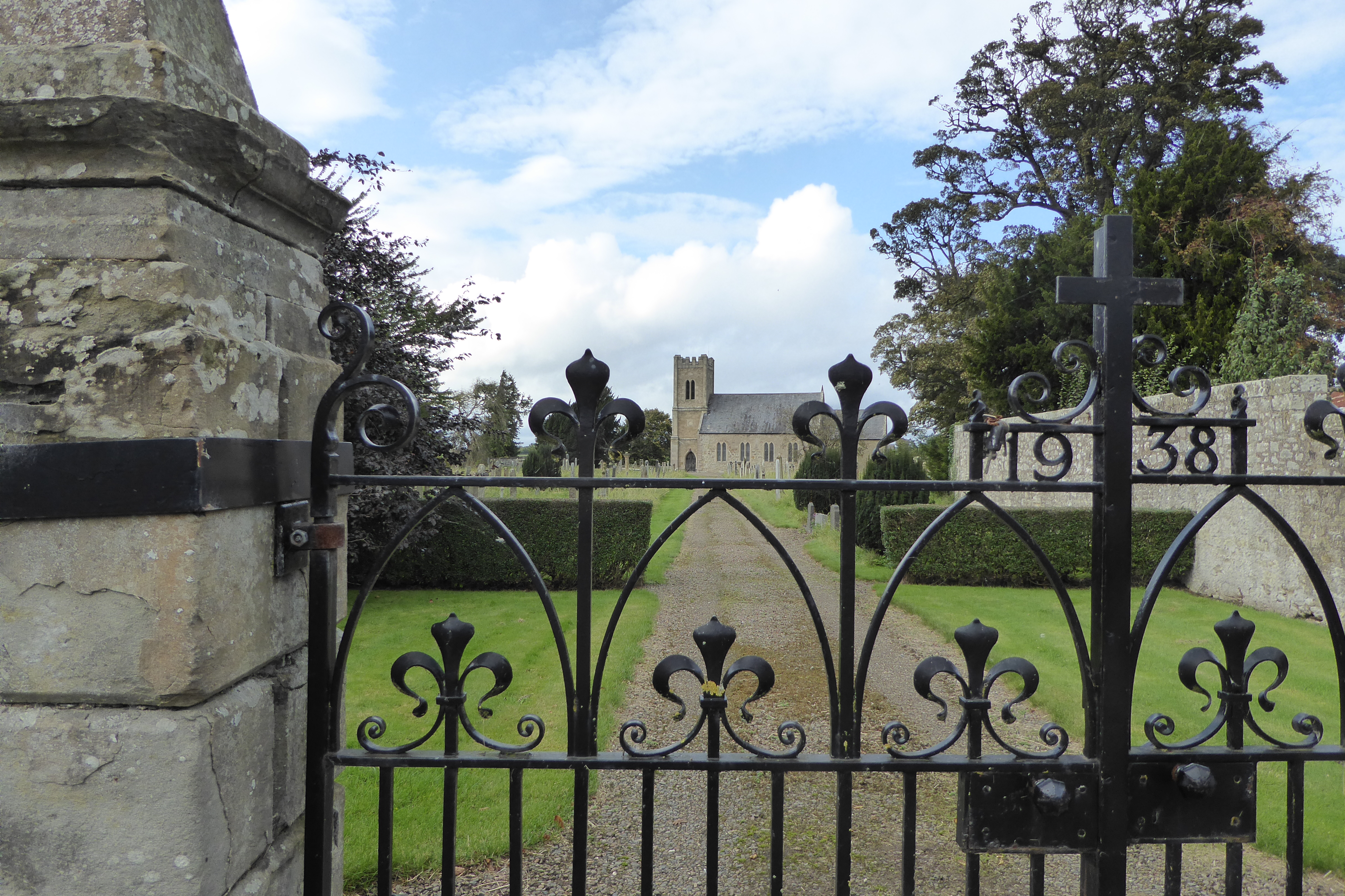 The Church of St Cuthbert and its wrought iron gates, which bear the date 1938